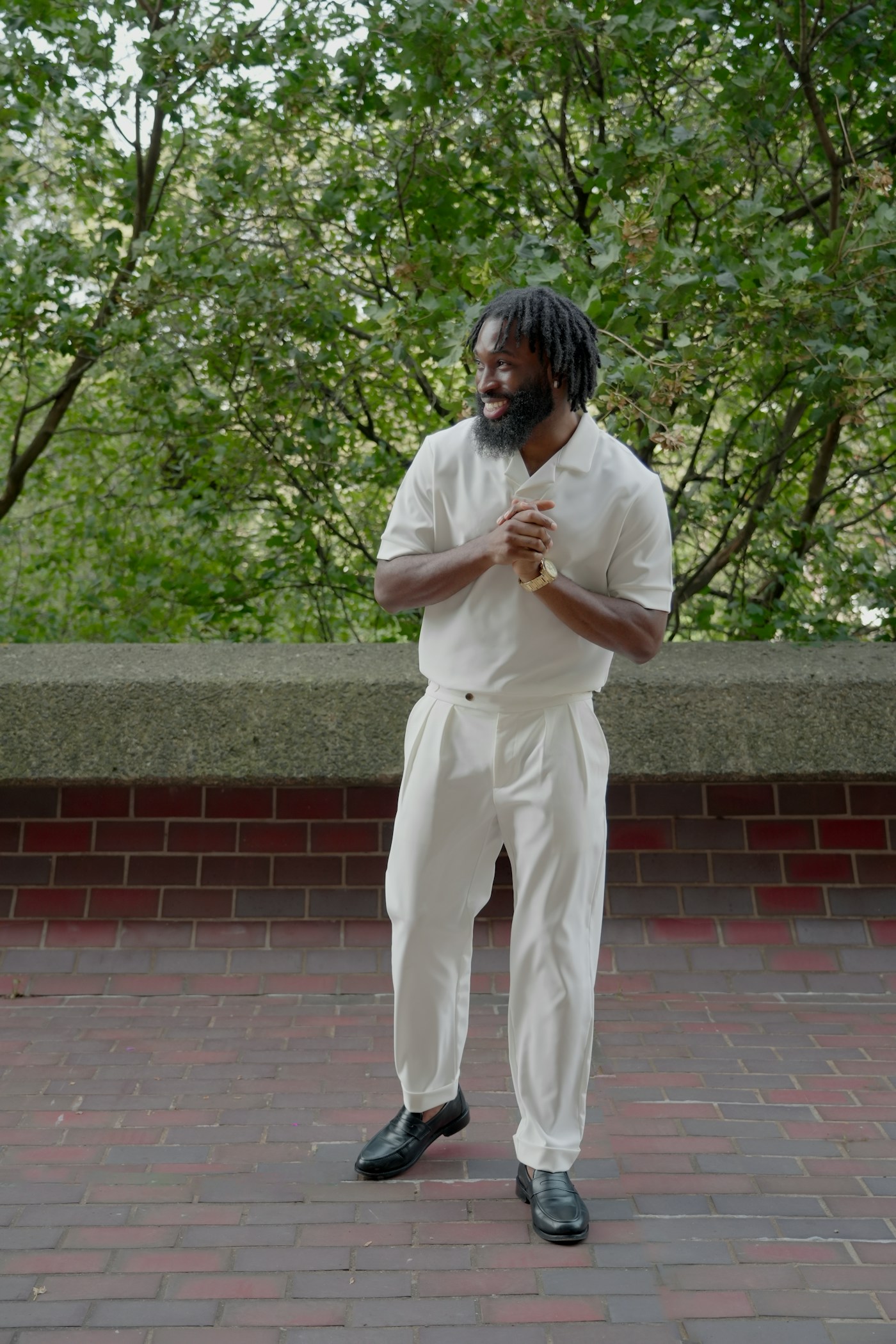 Fashion portrait of a man in a white suit against architectural brickwork