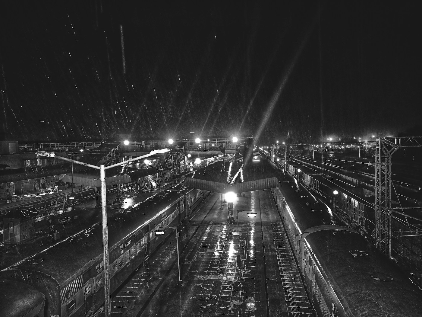 Train platform glowing under bright lights on a rainy night
