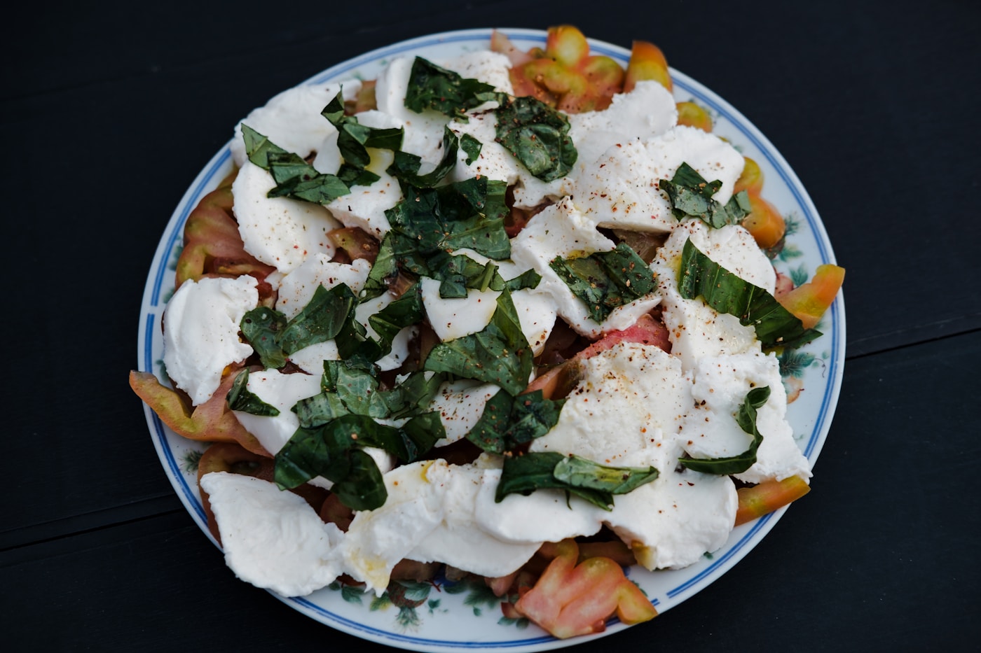 Heirloom tomatoes, mozzarella, and basil arranged on a plate